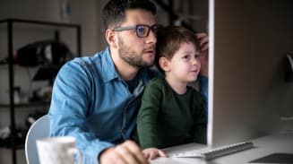 Man working on laptop with his young son