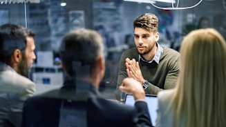 Young businessman talking to human resource team during a job interview in the office. The view is through glass.