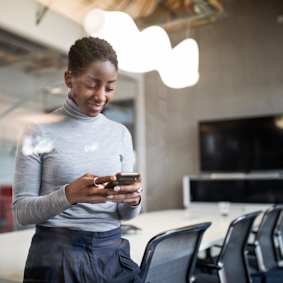 woman standing in conference room looking at cell phone