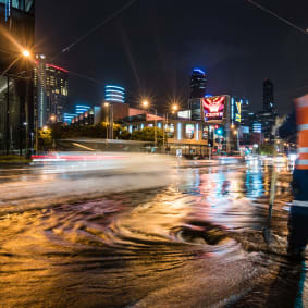 worker looking at flooded city street at night