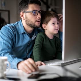 Man working on laptop with his young son